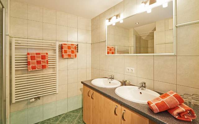 Badezimmer mit Doppelwaschbecken, Dusche, WC und Handtuchwärmer