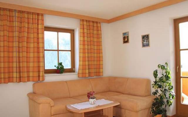 Living room with comfortable couch and balcony with a view of the mountain panorama in the Großarltal